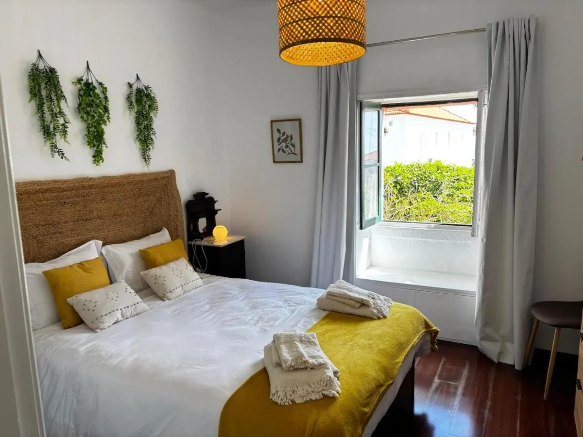 Quarto com cama de casal, colcha amarela e cabeceira de palha